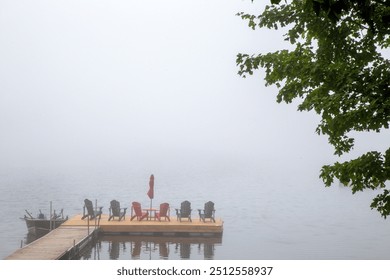 Foggy late summer early fall morning Spring Lake. Calm still water. Floating wood wooden dock. Fog foggy mist misty. Quiet peaceful. Muskoka Adirondack chairs umbrella motor boat. Tree. Reflection.  - Powered by Shutterstock