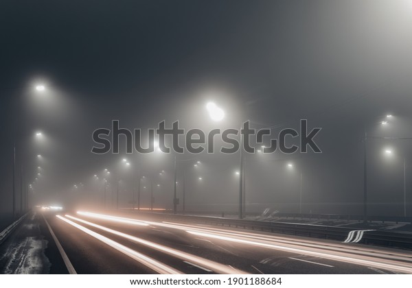 Foggy\
misty night road illuminated by street\
lights.