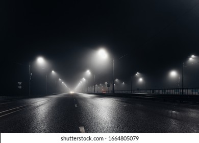 Foggy misty night road and overhead pedestrian bridge illuminated by street lights - Powered by Shutterstock