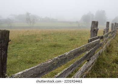 Foggy morning in the countryside. View of the old wooden fence, fields and wooden houses in the fog. Summer in the village. Misty rural landscape. Poor visibility in mist. Vologda region, Russia. - Powered by Shutterstock