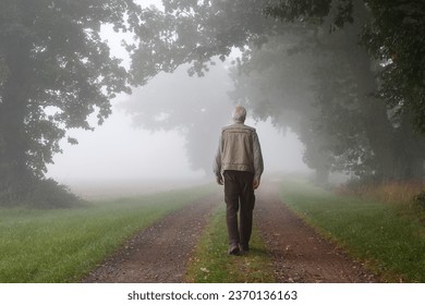 The Foggy Morning Walk of an Elderly Man Amidst Ancient Guardians of the Landscape. - Powered by Shutterstock