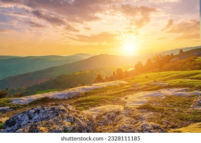 Foggy sunset or dawn in the mountains covered with grass and cloudy dramatic sky. Mountain landscape.
