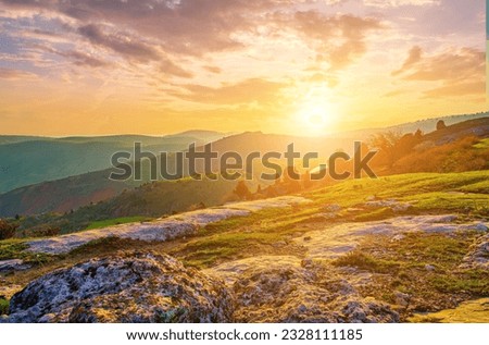 Foggy sunset or dawn in the mountains covered with grass and cloudy dramatic sky. Mountain landscape.