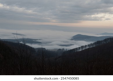 Foggy valley landscape with hills and leafless trees under a moody cloudy sky at sunrise. Mátra, Hungary - Powered by Shutterstock