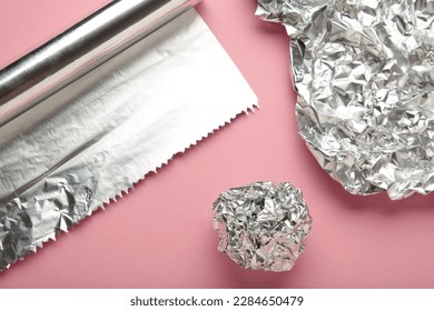 Foil ball with aluminium rolls on pink background. Top view