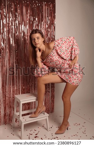 foil pink rain curtain for the photo zone. birthday barbie photo. beautiful stylish girl in a short pink dress in the studio. 16th birthday. romantic date wear pink cute dress 