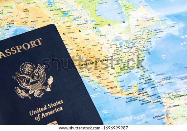 The foil-stamped dark blue front\
cover of an American passport set on a world map\
background.