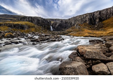 Folaldafoss waterfall and glacial river, Berufjordur, East Fjords, Iceland. Long exposure shot of fast flowing water. Autumn colours in the surrounding vegetation. 