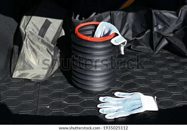 Foldable\
bucket with work gloves in the trunk of a\
car