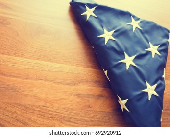 Folded American flag into a triangular shape on an old walnut office table with space for text or image