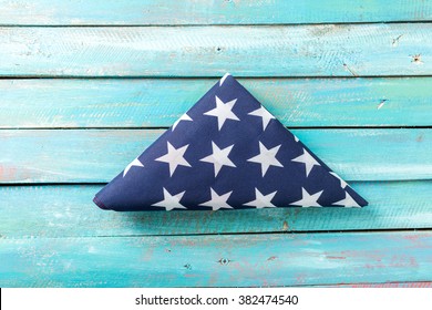 Folded American Flag On Blue Distressed Wood Background