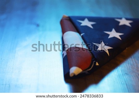 Folded American Flag Triangle on Wooden Table with Blue Lighting