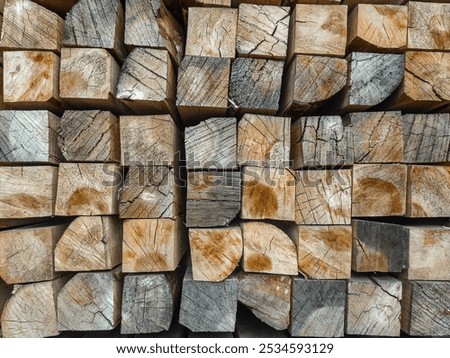 A folded bar in a stack. The end part is made of treated wooden beams. Background with a wood texture. Industrial texture of lumber. A close-up background image of a stack of wooden beams.