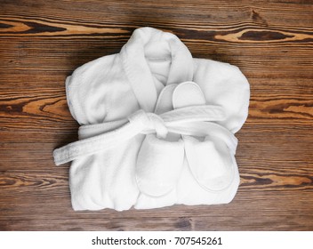 Folded Bathrobe And Bathing Slippers On Wooden Background