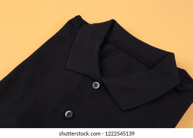 Folded Black Shirt On Orange Pastel Background
