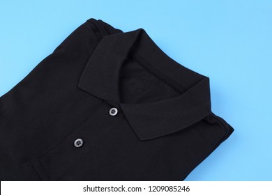 Folded Black Shirt Polo On Blue Pastel Background