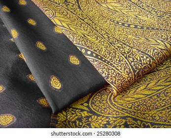 A Folded Black And Yellow Saree With Floral Designs