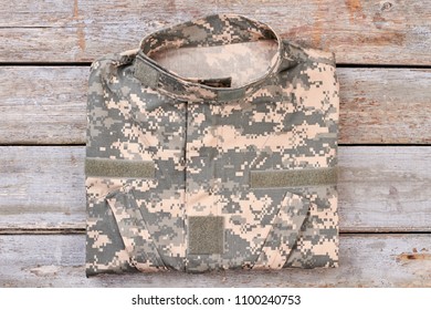 Folded Camouflage Military Jacket. Top View, Flat Lay. Wooden Desk Background.