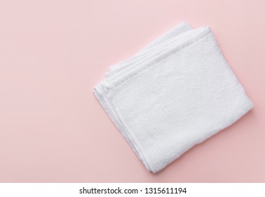 Folded clean white fluffy terry towel on pastel pink background. Minimalist flat lay. Women's baby hygiene laundry body care wellness well-being concept. Copy space 庫存照片