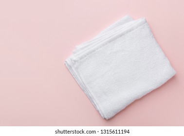 Folded Clean White Fluffy Terry Towel On Pastel Pink Background. Minimalist Flat Lay. Women's Baby Hygiene Laundry Body Care Wellness Well-being Concept. Copy Space