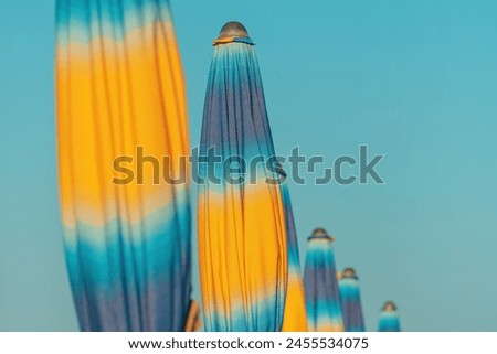 Similar – Colorful striped, closed parasol in close-up on the beach at sunset