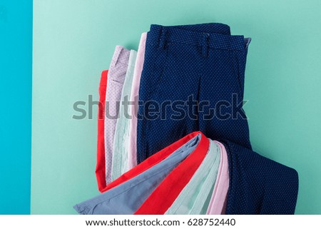 Folded colorful pants and jeans on mint background. Top view