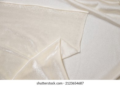 Folded cream-colored fabric texture background. This velvet fabric is made of 100% polyester.