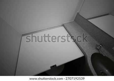 Folded down baby changing table inside an airplane lavatory.