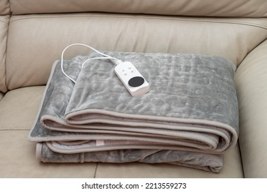 folded electric blanket with controller on a sofa - Shutterstock ID 2213559273