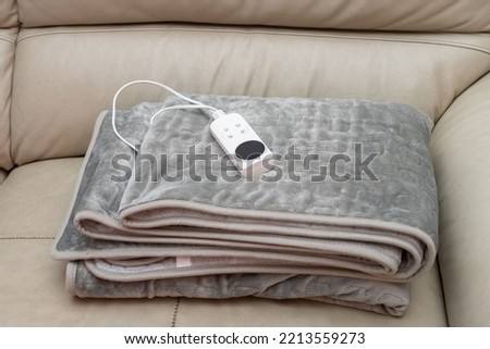 folded electric blanket with controller on a sofa