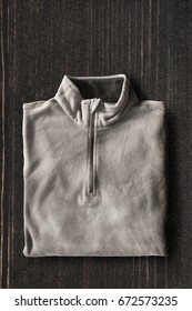 Folded Gray Fleece Sweatshirt On Dark Wooden Background