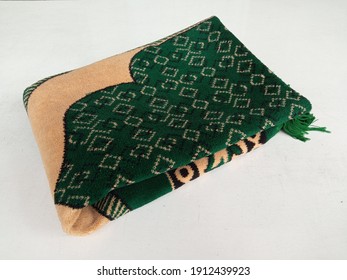 A Folded Green Muslim Prayer Mat In White Background