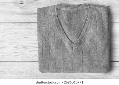 Folded grey wool pullover lying on white wooden background