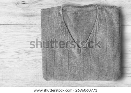 Folded grey wool pullover lying on white wooden background
