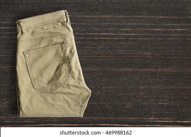 Folded Khaki Pants On Dark Wooden Background