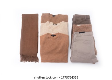 Folded Knitted Three Sweater  And Three Colorful Khaki Pants With Brown Scarf On White Background, Top View


