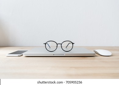 folded laptop at workplace with eyeglasses, smartphone and mouse - Powered by Shutterstock