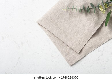 Folded Linen Napkin With Green Plant On Marble Table Background, Top View