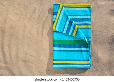 Folded New Towel On Sand, Top View With Space For Text. Beach Object