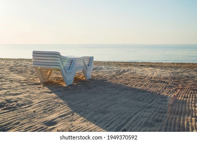 Folded plastic deck chairs on a deserted beach by the sea. The failure of the sea season. Closed public beaches. - Shutterstock ID 1949370592