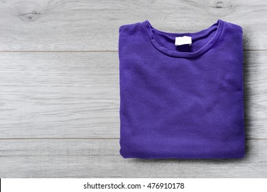 Folded Purple Sweatshirt On White Wooden Background