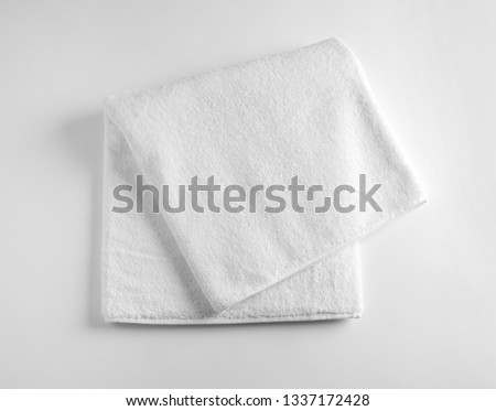 Folded soft terry towel on light background, top view