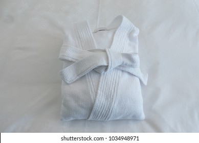 Folded Spa Bathrobe : Isolated  White Bath Robe Folded On The Bed In Hotel Room.  Prepare For Shower And Spa.