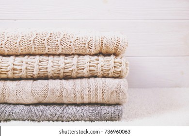 Folded sweaters gradient white wooden background