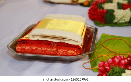 Folded Traditional Kerala Kasavu Saree And Red Silk Saree On A Dish During Indian Wedding 