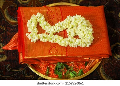 Folded traditional Kerala kasavu saree and red silk saree on a dish during Indian weddin