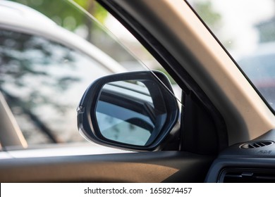 Folded Wing Mirror Of A Compact Modern Car, With A Side Window Glass Drop Down For A Ventilation, Parked In A Parking Lot During The Morning Time With A Nice Sun Rise Shining. Seeing From A Back Seat.