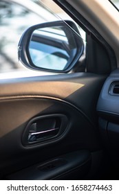 Folded Wing Mirror Of A Compact Modern Car, With A Side Window Glass Drop Down For Ventilation, Seeing An Inner Car Door Handle. Car Parked In A Parking Lot During The Morning Time With Sun Rise.