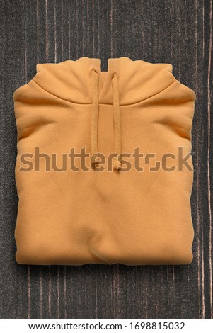 Folded yellow hoody on dark wooden background
