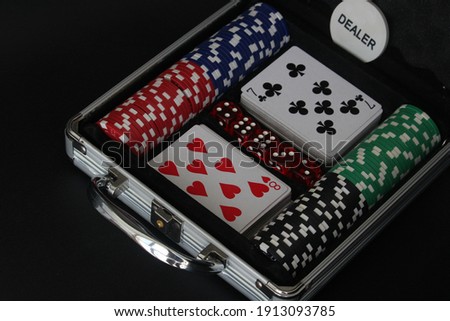 Folder with chips, cards and dice for games on black background.